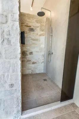 a shower in a bathroom with a stone wall at Kalamaki Luxury Suites in Kalamaki Chanion