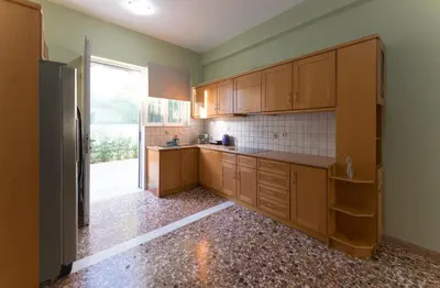 a kitchen with wooden cabinets and a large window at Cityscape House in Chania Town