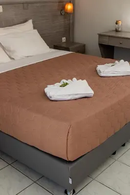 a bed with two towels sitting on top of it at Anna Katerina Apartments in Plataniás