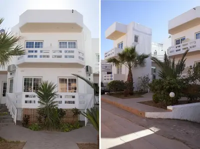 a white building with a palm tree in front of it at Anna Katerina Apartments in Plataniás