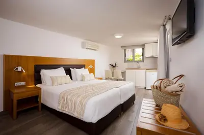 a bedroom with a large bed and a kitchen at Stellina Village in Kato Daratso