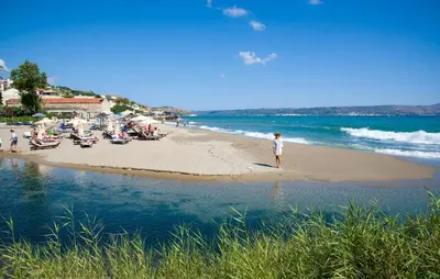 a person standing on a beach near the water at Kalyves Beach Hotel in Kalyves