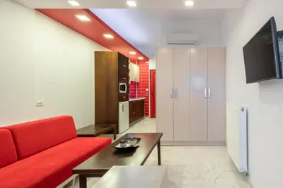 a living room with a red couch and a table at Sevach Apartments in Kalamaki Chanion