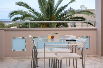 a table and chairs on a balcony with a palm tree at Sevach Apartments in Kalamaki Chanion