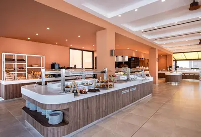 a restaurant with a counter with food on it at Kiani Beach Resort Family All Inclusive in Kalyves