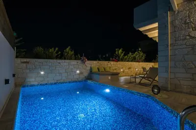 a swimming pool in a backyard at night at Villa Sirocos in Stalos