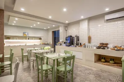 a dining room with tables and chairs and a kitchen at Airis Boutique Hotel & Suites - For adults only in Kato Daratso