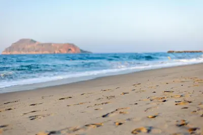 a beach with footprints in the sand and the ocean at Blue Dome Hotel in Plataniás