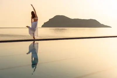 a woman in a white dress dancing on the beach at Blue Dome Hotel in Plataniás