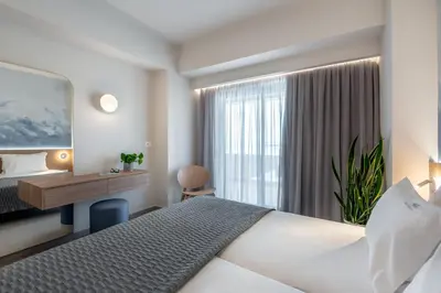 a hotel room with a bed and a desk and a window at Blue Dome Hotel in Plataniás