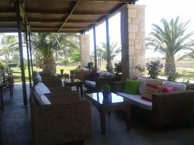 a patio with couches and tables and palm trees at Kallicrates Village in Frangokastello
