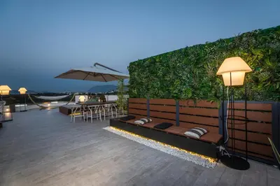 a patio with a bench and tables and an umbrella at The Hill House Villa in Kato Daratso
