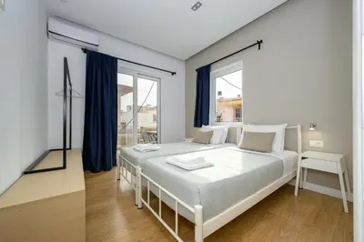a white bedroom with a large bed with blue curtains at Modern Spacious Apartment in Kissamos