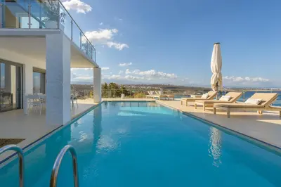 a large swimming pool with chairs and a house at Villa Anton by Cura Villas Collection in Kalathas