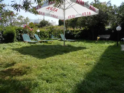 a group of chairs under an umbrella in the grass at Ilona Apartments Chania in Kato Daratso