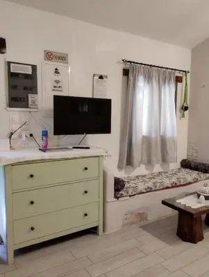a bedroom with a bed and a dresser with a television at Olea Cottage in Galatás