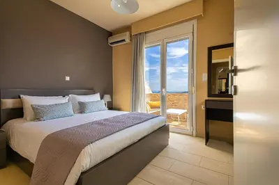 a bedroom with a large bed and a large window at Theo Villas With Sea View in Marathokefála