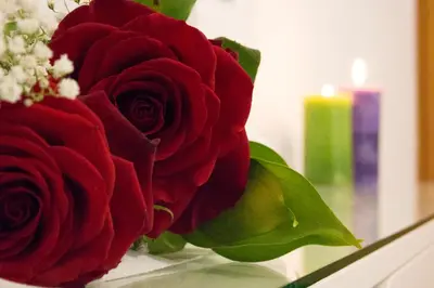 a bouquet of red roses in a vase with a candle at Michael Apartments in Agia Marina Nea Kydonias