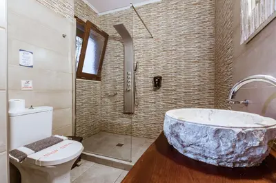 a bathroom with a large marble tub next to a toilet at Deluxe Hotel in Chania Town