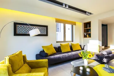 a living room with a couch and yellow pillows at Villa Amelia I Free 8 seater mini van & pool in Kalathas