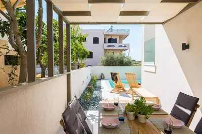 an outdoor patio with tables and chairs on a balcony at Villa Amelia I Free 8 seater mini van & pool in Kalathas