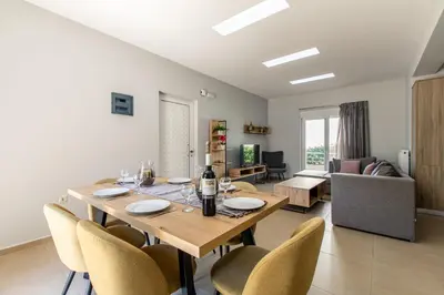 a dining table and chairs in a living room at Villa Neaira in Vatólakkos