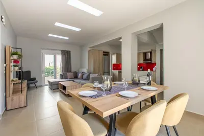 a dining room and living room with a table and chairs at Villa Neaira in Vatólakkos