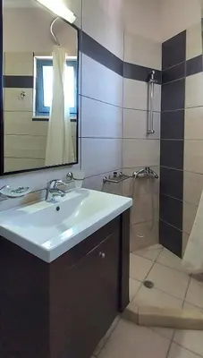 a bathroom with a sink and a mirror and a shower at Thealia in Karefilianá
