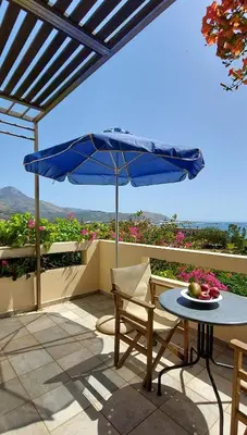 a table and a blue umbrella on a patio at Doma Apartments in Falasarna