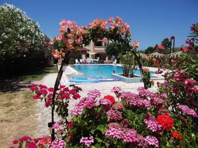a garden with flowers in front of a swimming pool at Villa Rita Apartments A in Tavronitis