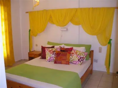 a bedroom with a green bed with yellow curtains at Villa Rita Apartments A in Tavronitis