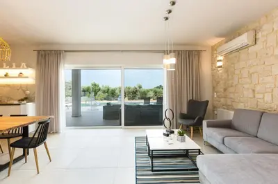 a living room with a couch and a table at Villa Aelia I Modern & Ideal for large groups in Galatás