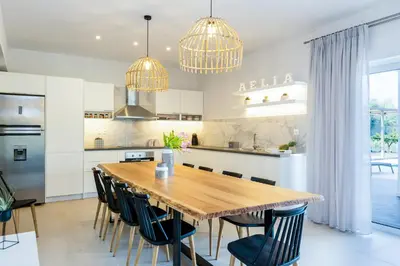 a kitchen and dining room with a wooden table and chairs at Villa Aelia I Modern & Ideal for large groups in Galatás