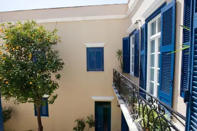 a building with blue shutters and a tree on a balcony at Suites Pandora in Chania Town