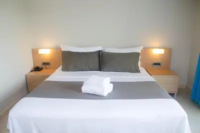 a bedroom with a white bed with two lamps at Nautilus Bay Hotel in Kissamos