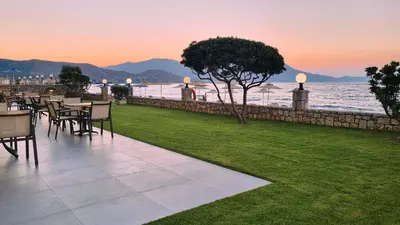 a row of tables and chairs with the ocean in the background at Sunny Bay Hotel in Kissamos