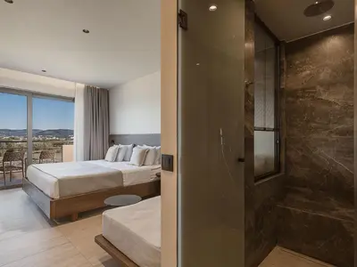 a hotel room with a bed and a glass shower at Sunny Bay Hotel in Kissamos