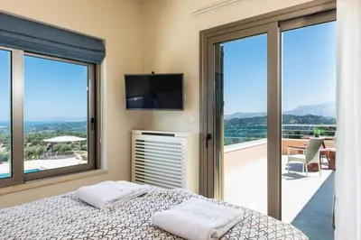 a bedroom with a bed and a balcony with windows at Angel Hill Villa in Xirokámbion