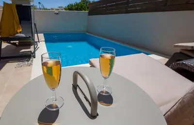 two glasses of champagne on a table next to a swimming pool at Villa Christy in Stalos