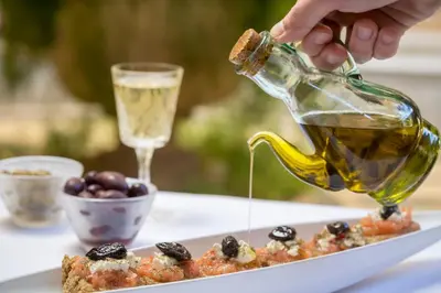 a person pouring olive oil into a plate of food at Casa Delfino Hotel & Spa in Chania Town