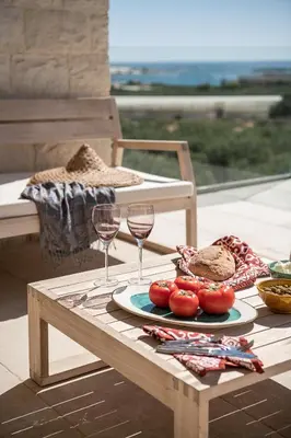 a table with a plate of food and two glasses of wine at Casa le Cicale in Falasarna