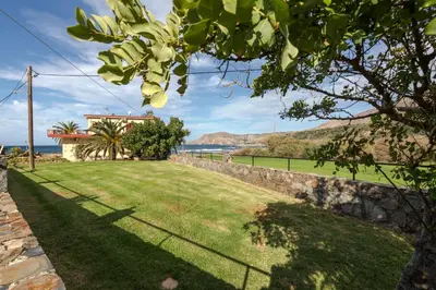a yard with a stone wall and a grass field at Pericles Beach Villa in Kissamos
