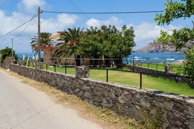 a stone wall next to a road next to the ocean at Pericles Beach Villa in Kissamos