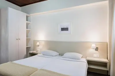 a white bedroom with a bed and two tables at Magia Apartments in Chania Town