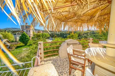 a patio with a table and chairs and a straw roof at Anemomili Village in Kissamos