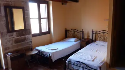 two beds in a room with a mirror and two windows at Kydonia Rooms in Chania Town