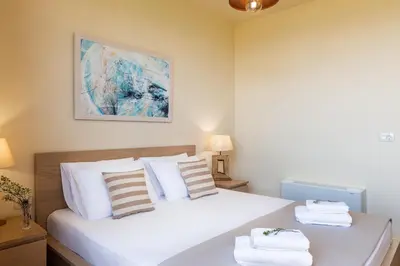 a bedroom with a bed with white sheets and pillows at Villa Kudos in Maleme