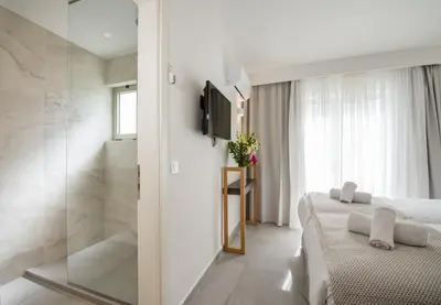 a bedroom with a bed and a shower and a television at Lotus Hotel Apartments in Kato Daratso