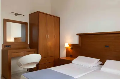 a bedroom with a bed and a chair and a mirror at Giorgi's Blue Apartments in Kalathas
