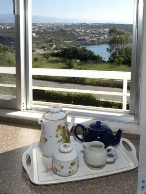a tray with two cups and a tea set in front of a window at Villas Michalis in Chorafakia